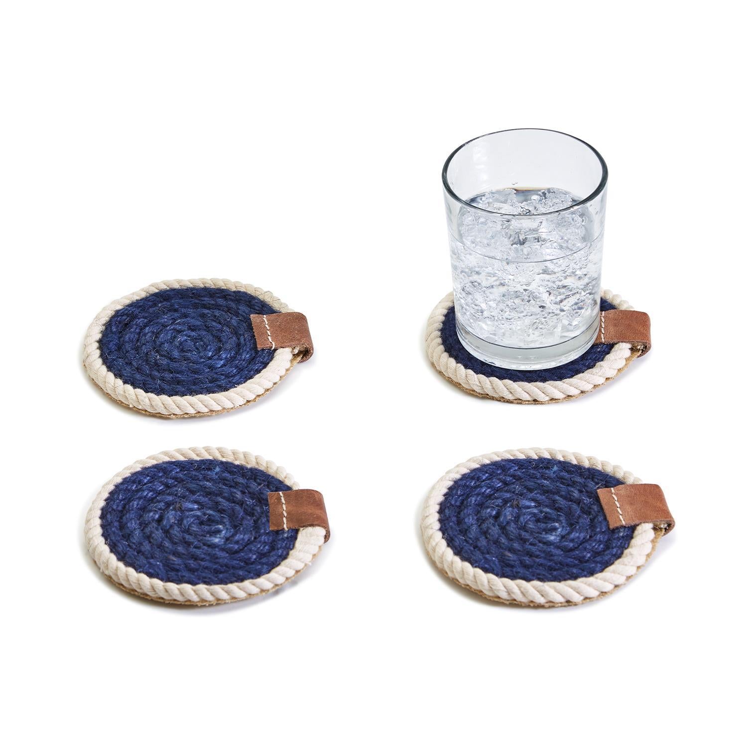 Set of four blue and white rope coasters with brown leather accents on a white background.