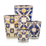 A collection of four Baobab scented candles in various sizes, featuring a vintage 24-carat gold and midnight blue print with a four-leaf clover design.