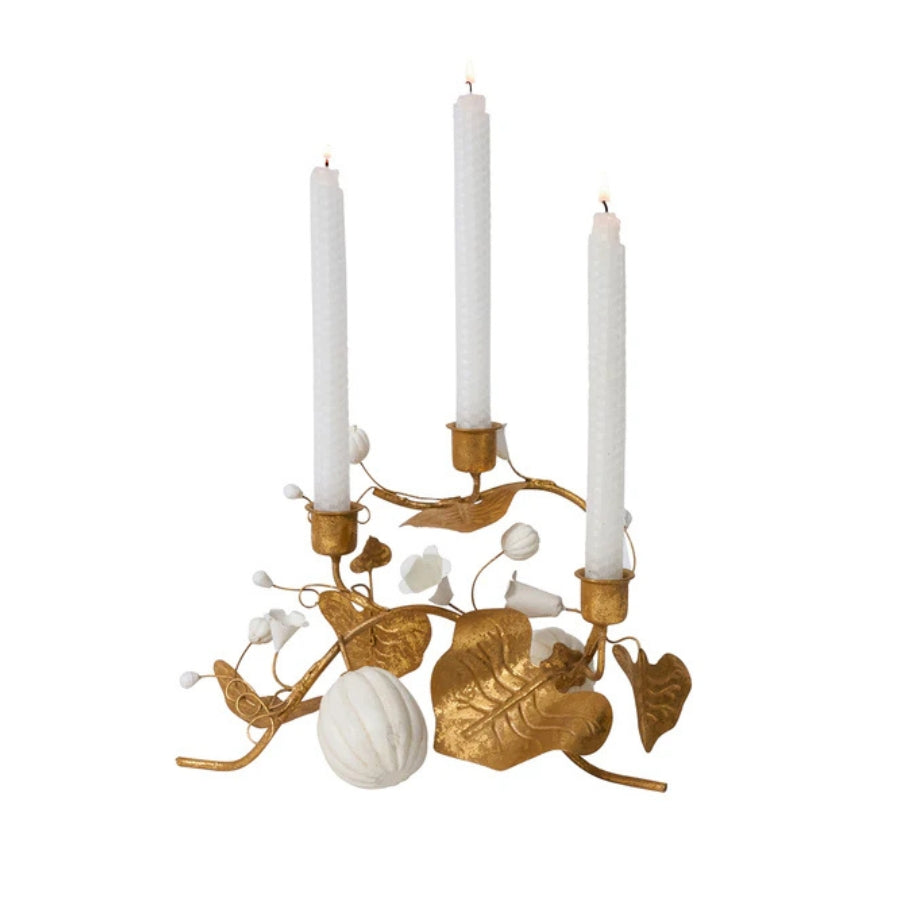 Decorative candle holder with gold leaves and white candles on a white background