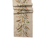 Decorative fall/autumn table runner with embroidered feather pattern on a white background