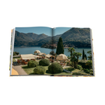 Open book showing a scenic view of a lakeside resort with mountains in the background.
